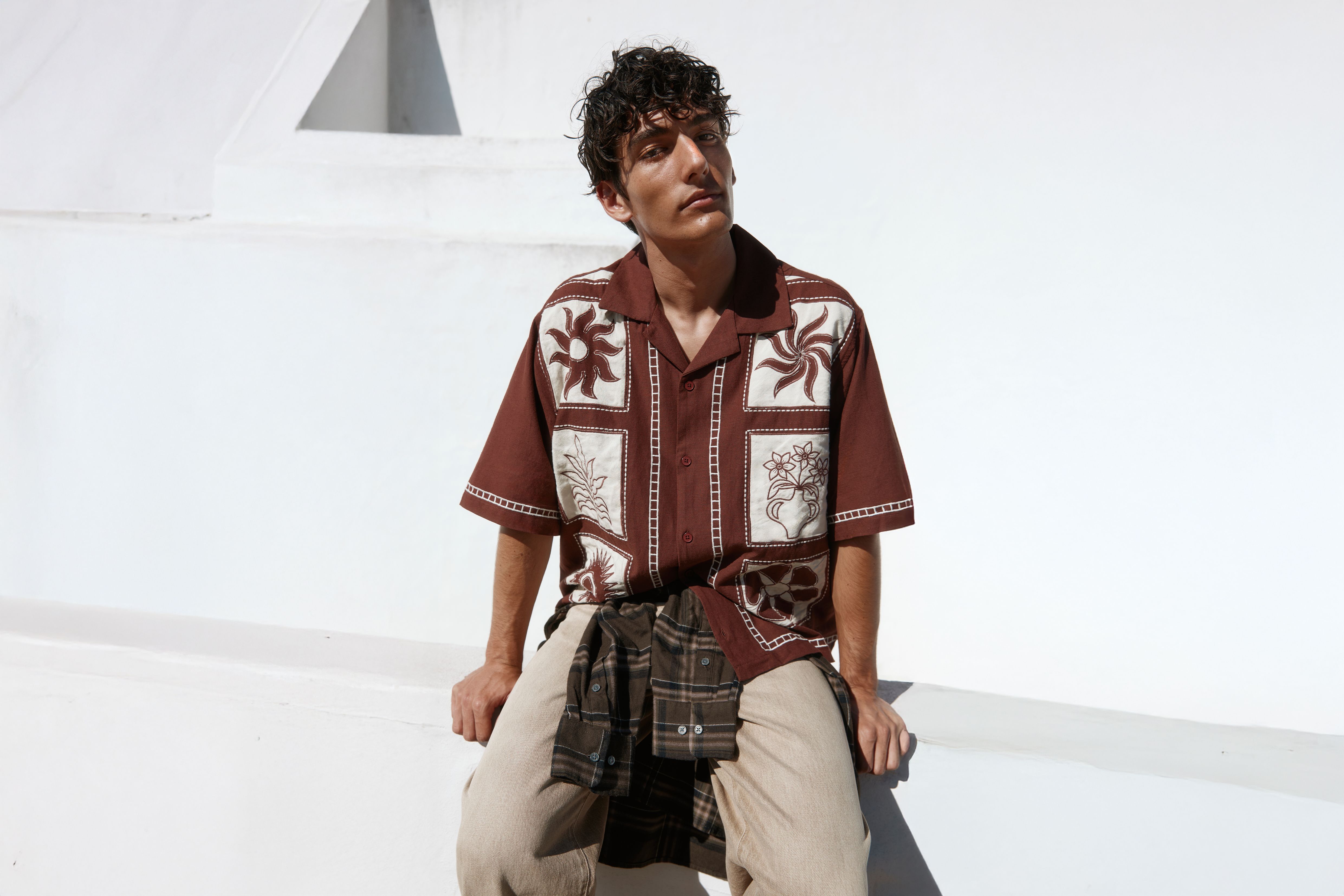 Man zit en draagt een bruin overhemd met korte mouwen