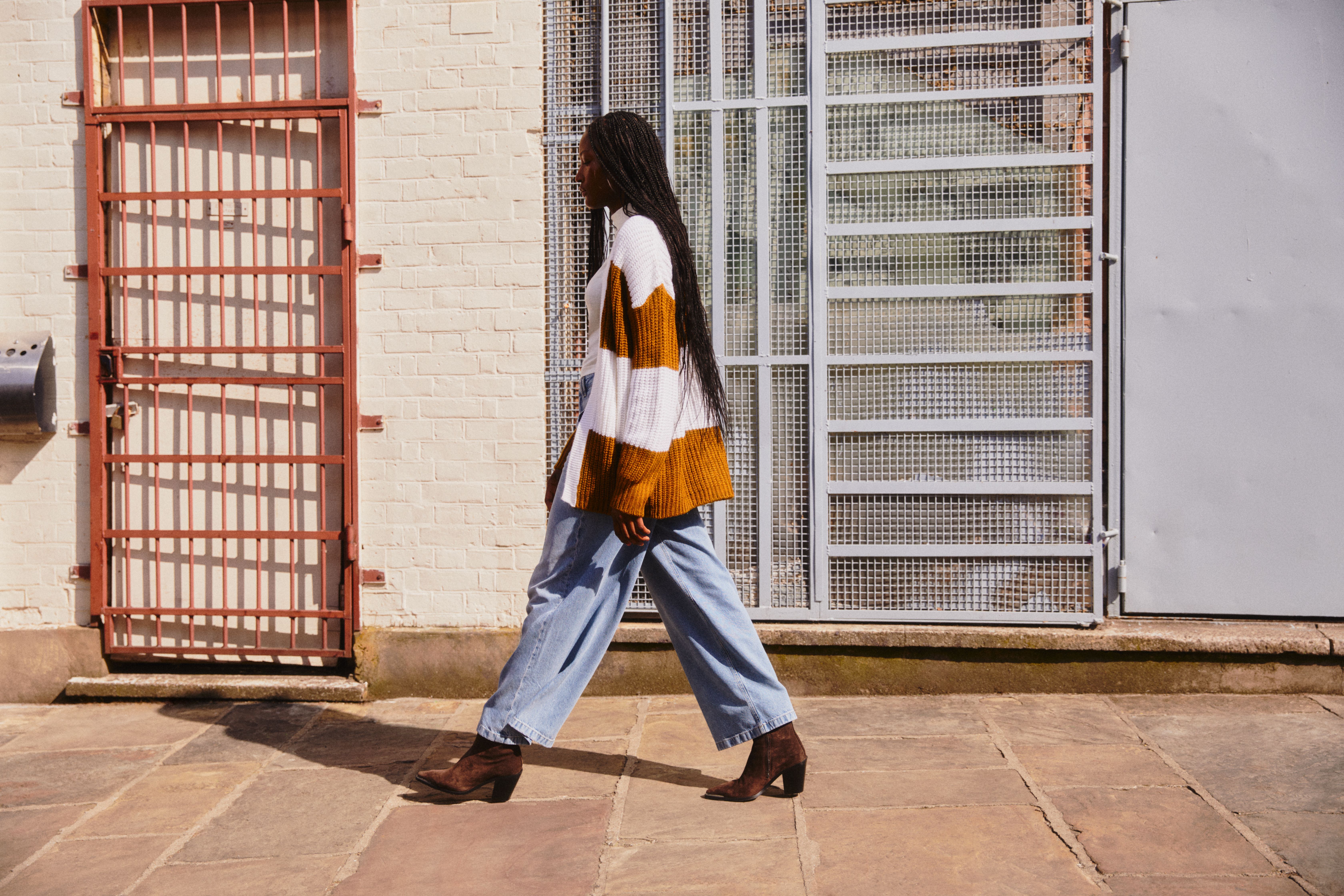 Vrouw loopt voorbij en draagt een stijlvolle, losse jeans en een gebreid jasje
